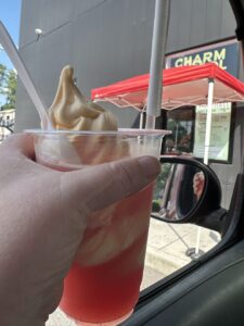 an orange ice cream float held up in a car window